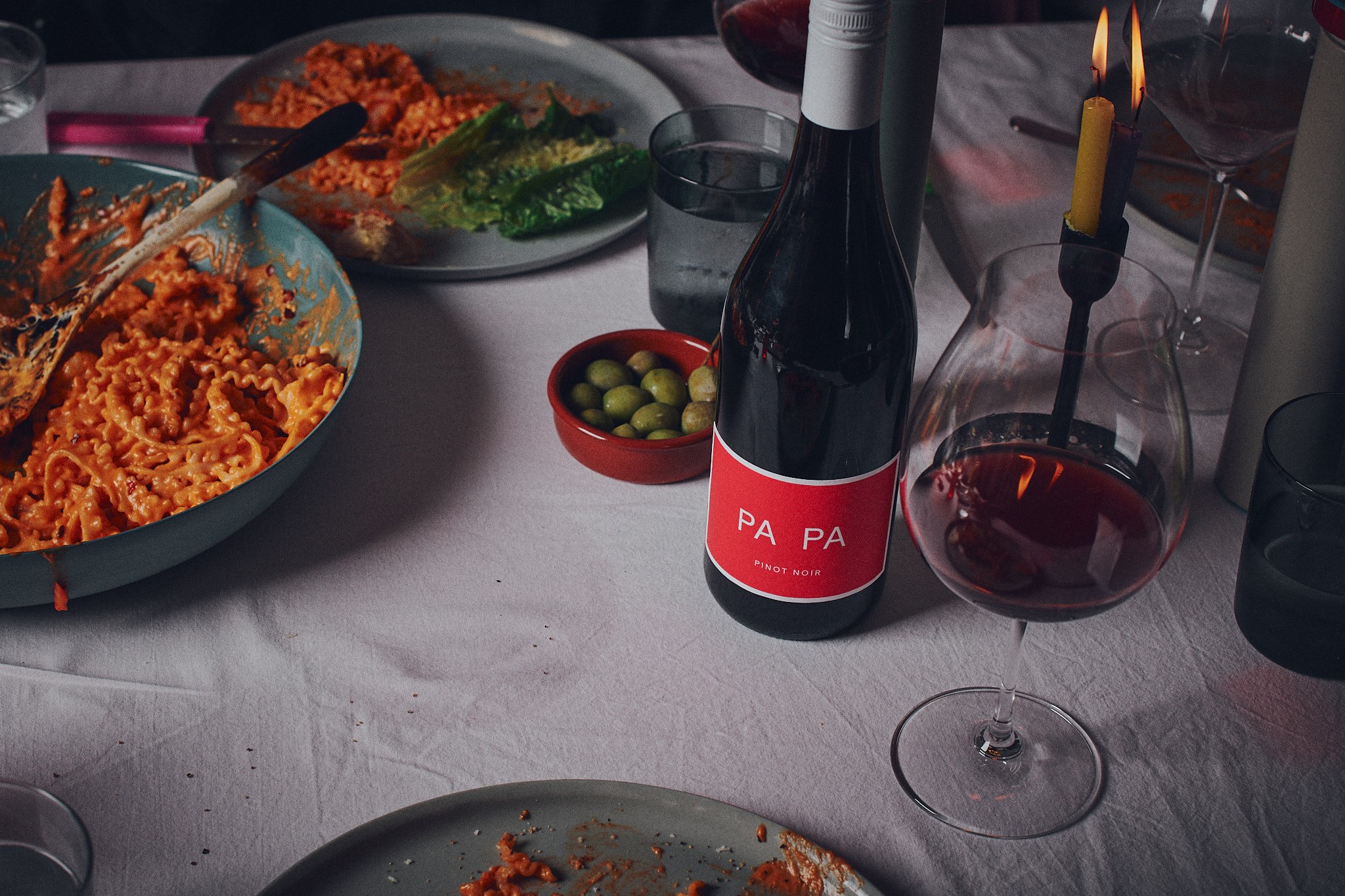 PA PA Pinot Noir on a table with pasta, olives and wine