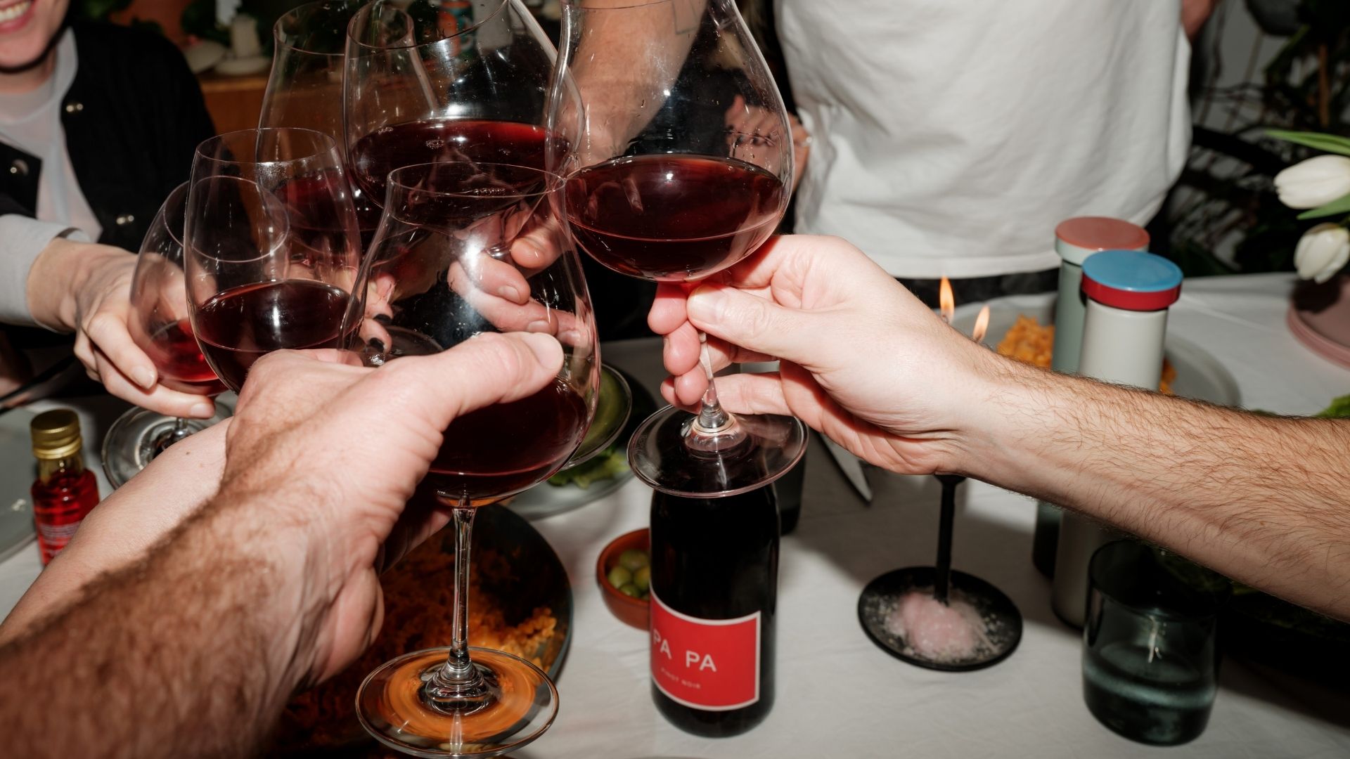 Friends raising glasses and sharing PA PA around a table